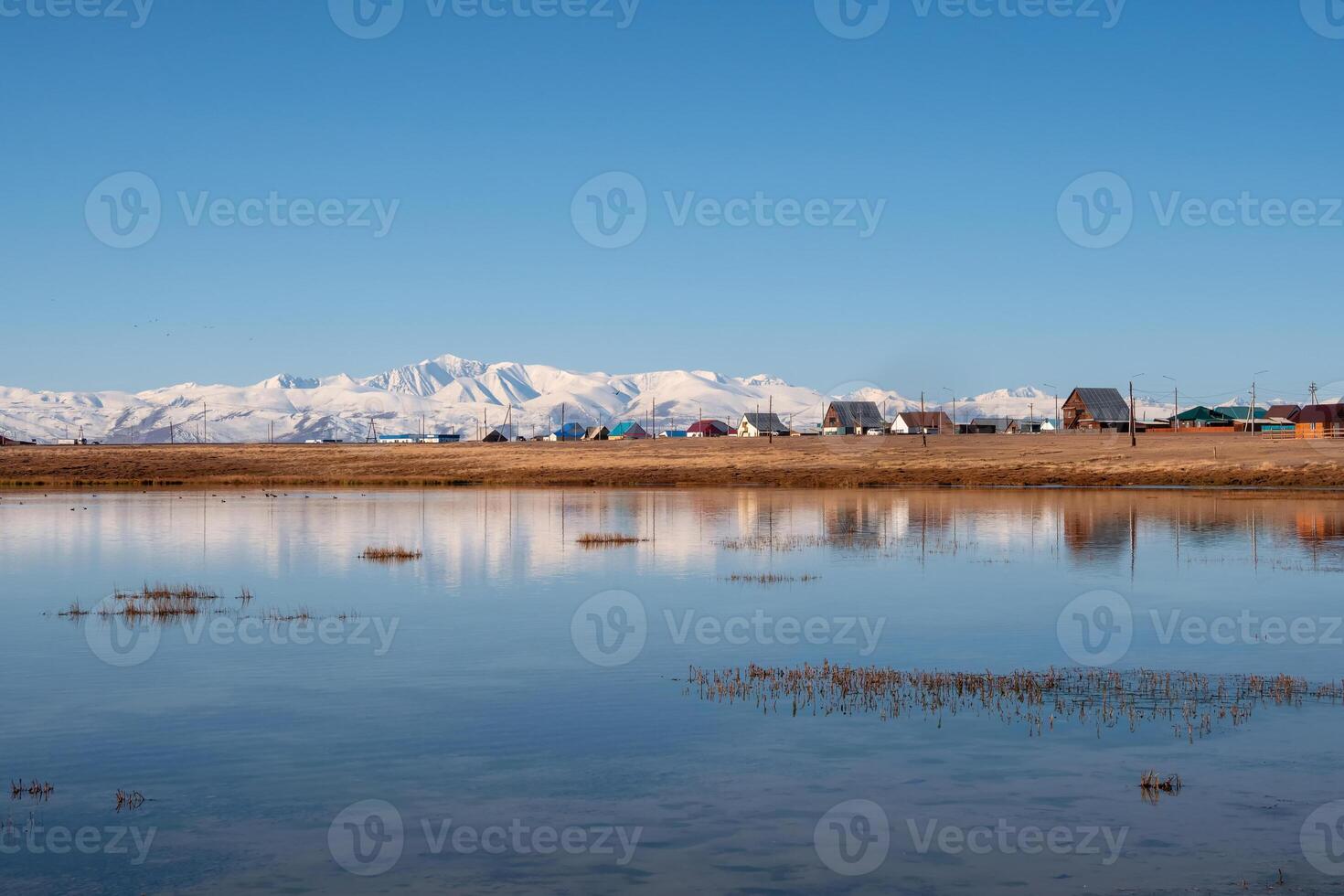 Landscape in the area Kosh-Agach Altai Republic. Village on the shore of the lake is reflected in the blue mirror surface of the water. photo