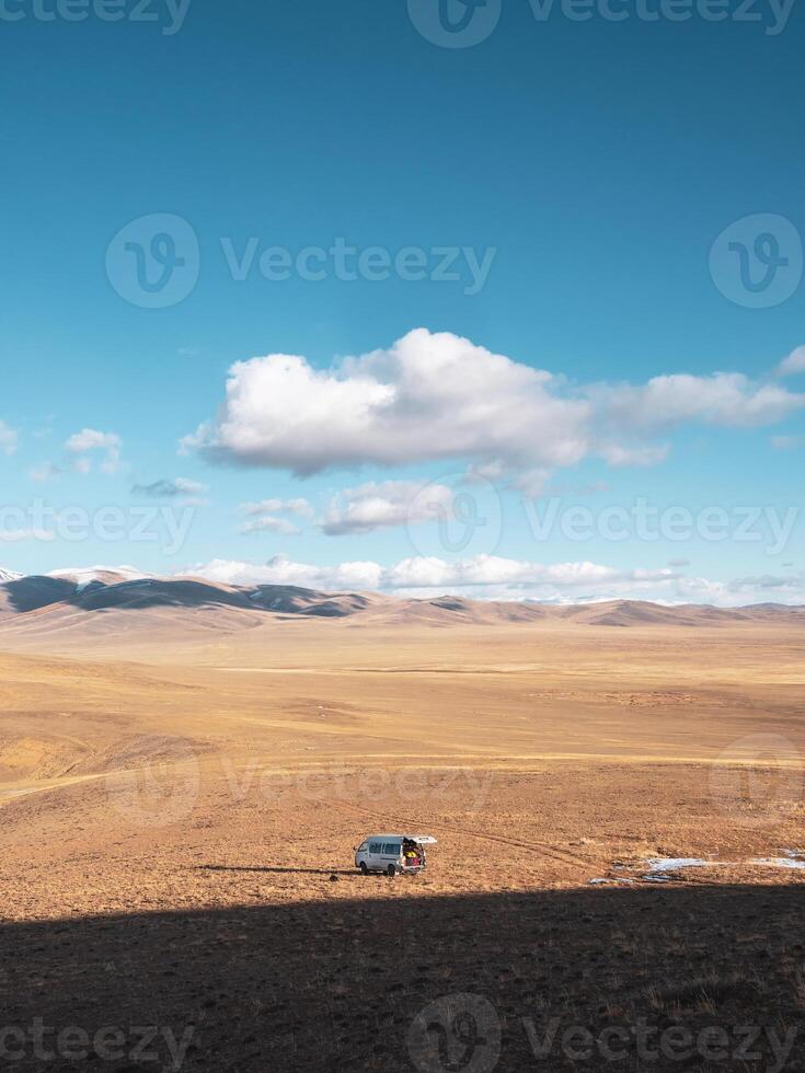 Old van parked in mountain steppe field, extreme travel on endless expanses. photo