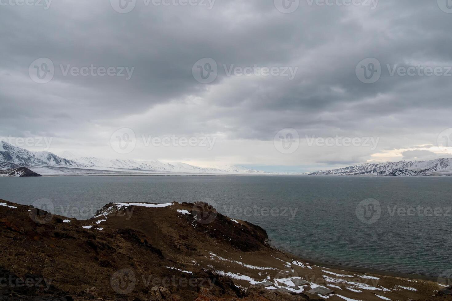 big lake Tolbo Nur on a cloudy morning. Mongolian natural landscapes near lake Tolbo-Nuur surrounded by mountains and rocks in north Mongolia. Migration of birds over the lake. photo