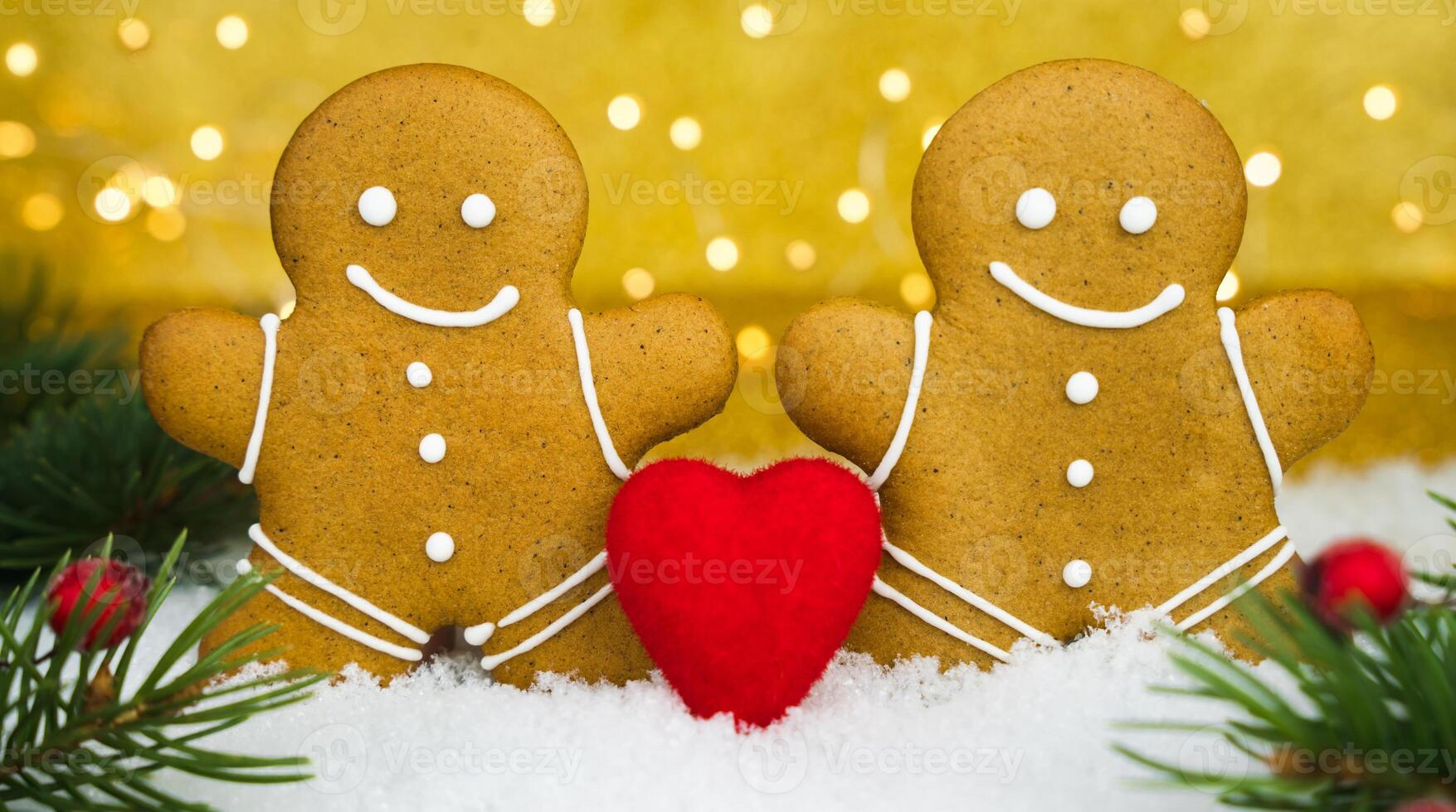 Two gingerbread men and red heart on a snowy background. Valentine's Day holiday concept. Close-up. Selective focus. photo