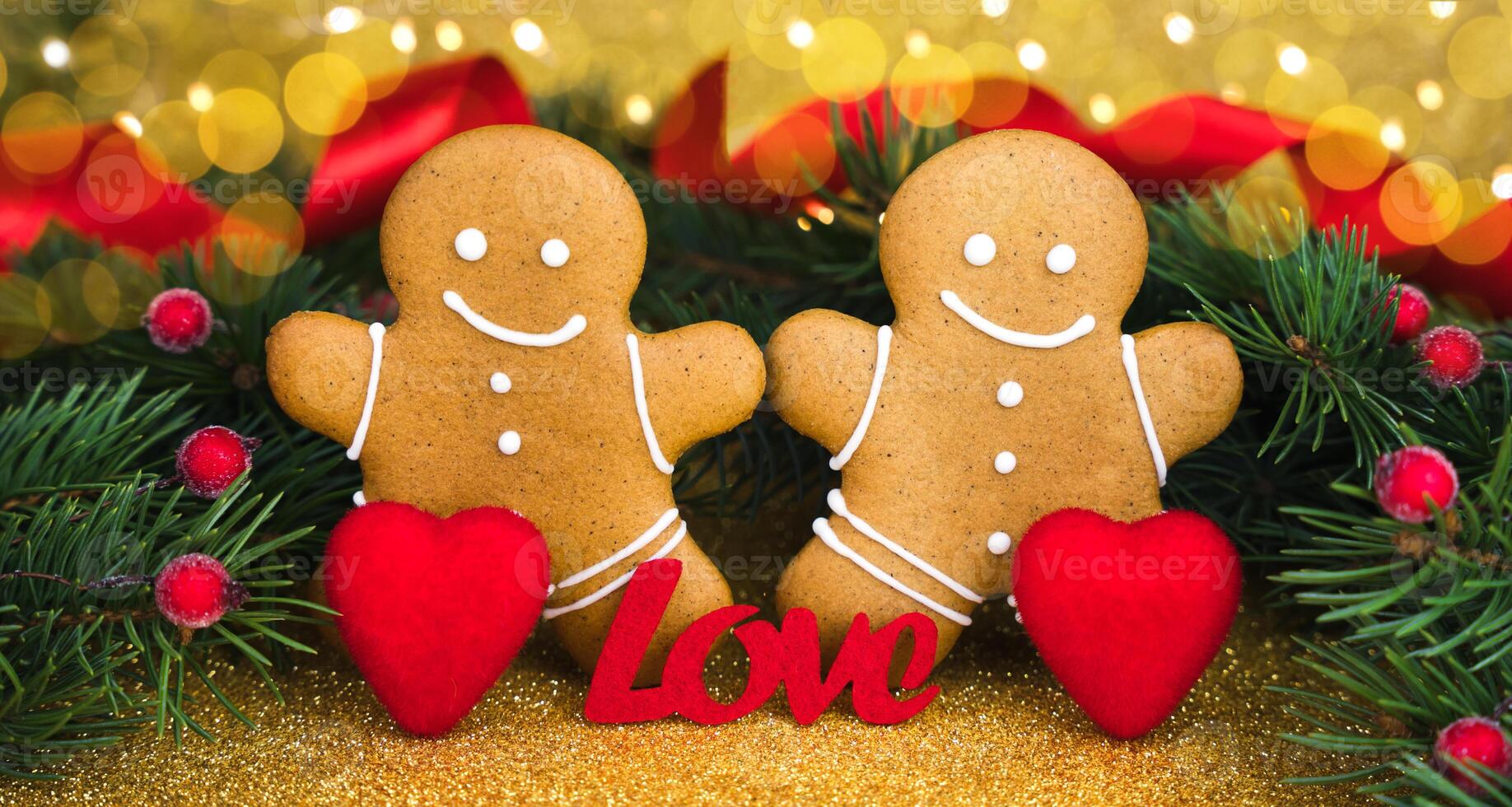 Two gingerbread men, two red hearts and the word LOVE on glitter golden background. Concept for Valentine's day. Close-up. photo