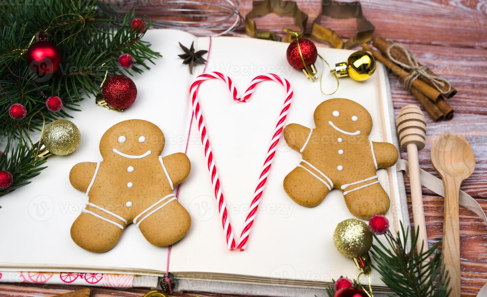 The concept of baking cookies for Christmas and Valentine's Day. Vintage recipe book, gingerbread men and heart of lollipops. DIY gifts for Christmas and Valentine's Day. Close-up. Top view. photo
