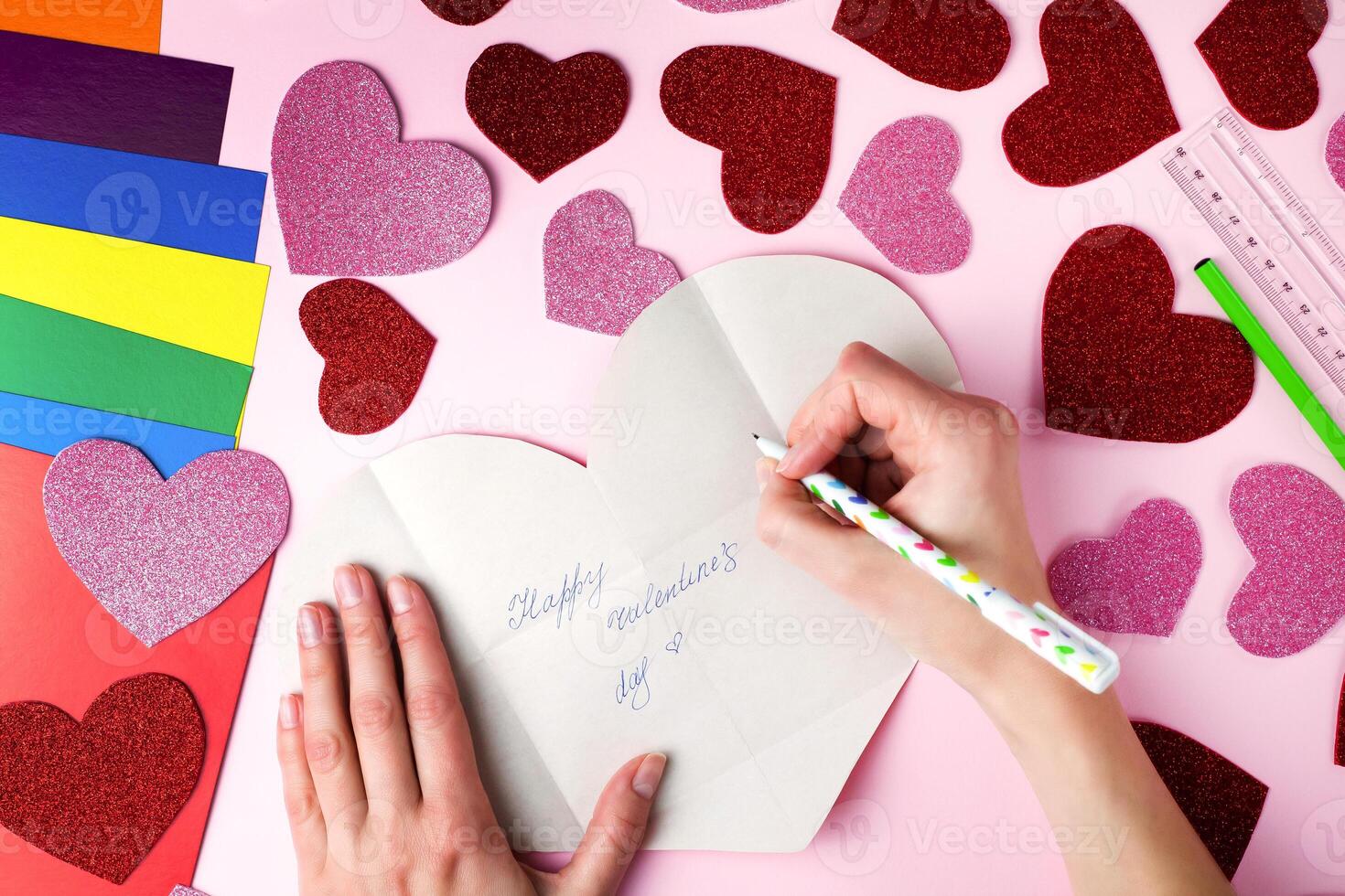 Woman's hands writes on paper heart the congratulation with Valentine's day. DIY concept for Valentine's day card crafts. Top view. Flat lay. Step by step photo instruction. Step 11.