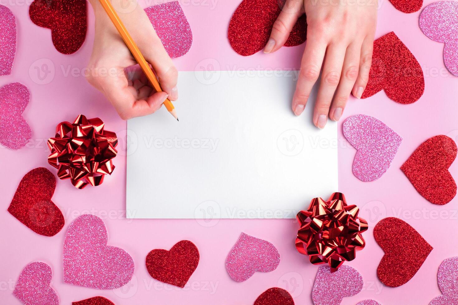 Woman's hands writes on blank sheet of paper the congratulation. Congratulation concept for Valentine's day, birthday. Top view. Copy space. photo