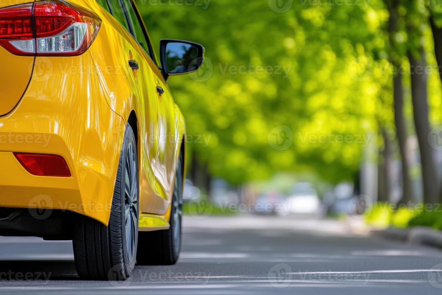 Yellow taxi driving along a tree-lined street with vibrant greenery and smooth asphalt surface, showcasing urban transportation during a sunny day photo