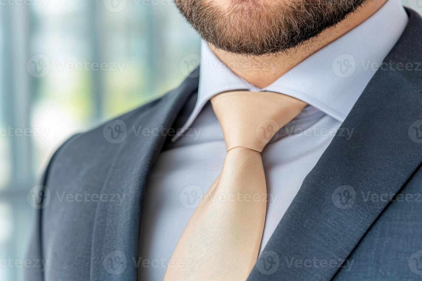 Professional man wearing a modern gray blazer and beige tie in a stylish office environment during daytime photo