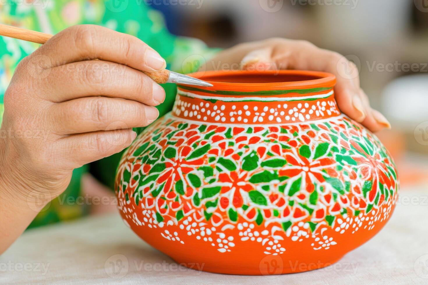Hands skillfully decorating an ethnic clay pot with vibrant natural dyes using traditional tools at a local craft workshop photo