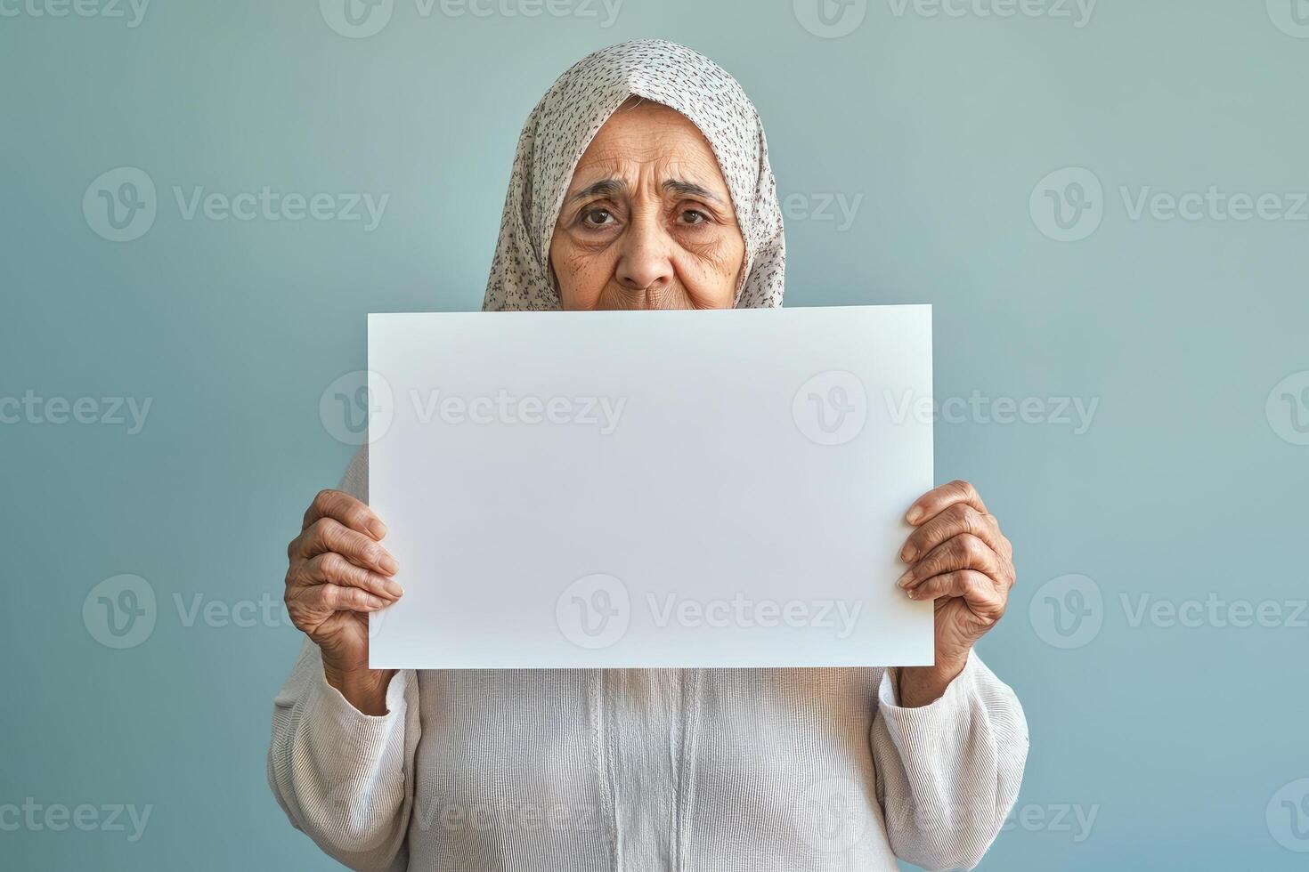 Elderly Woman in Headscarf Holds Blank White Sign photo
