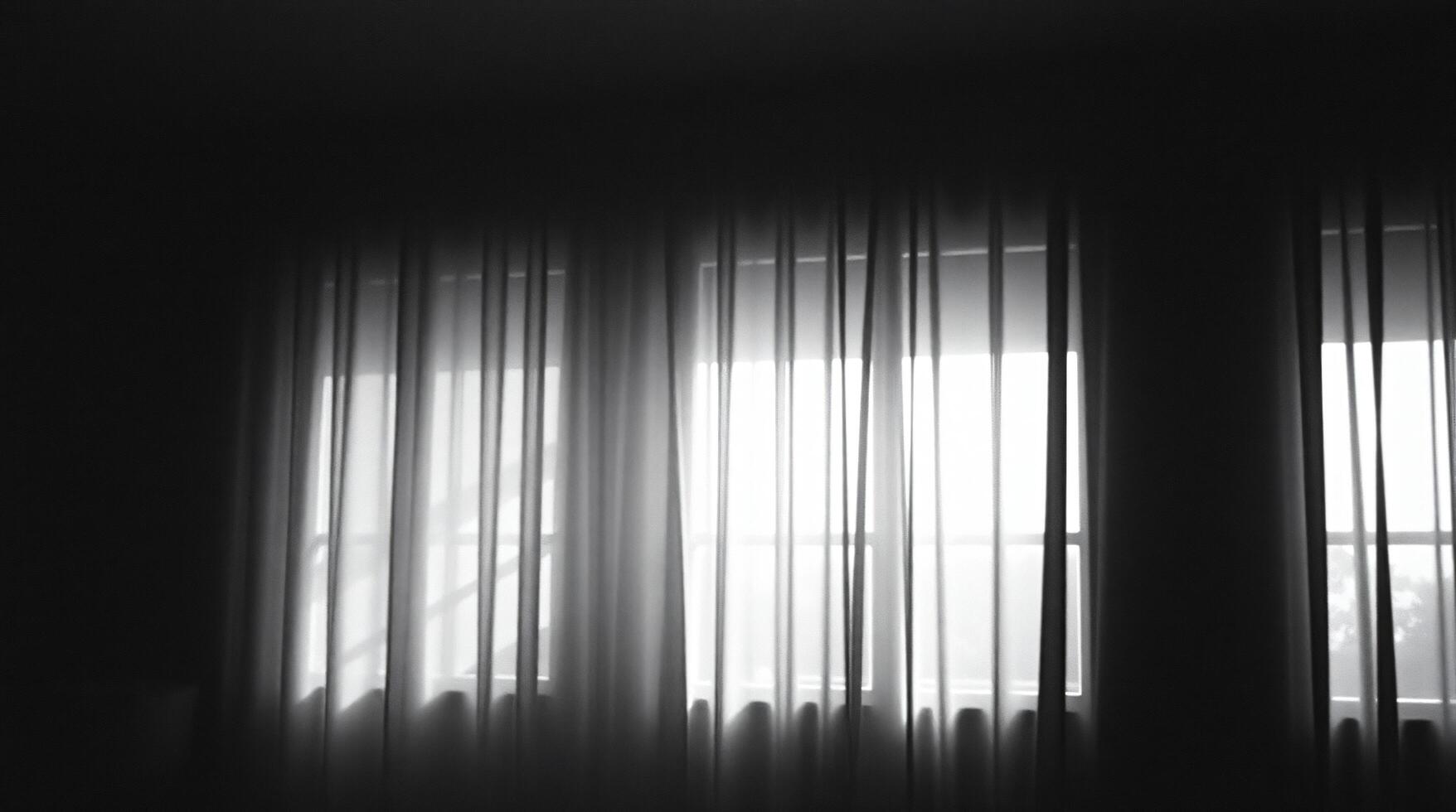 A black and white photo of a window with curtains
