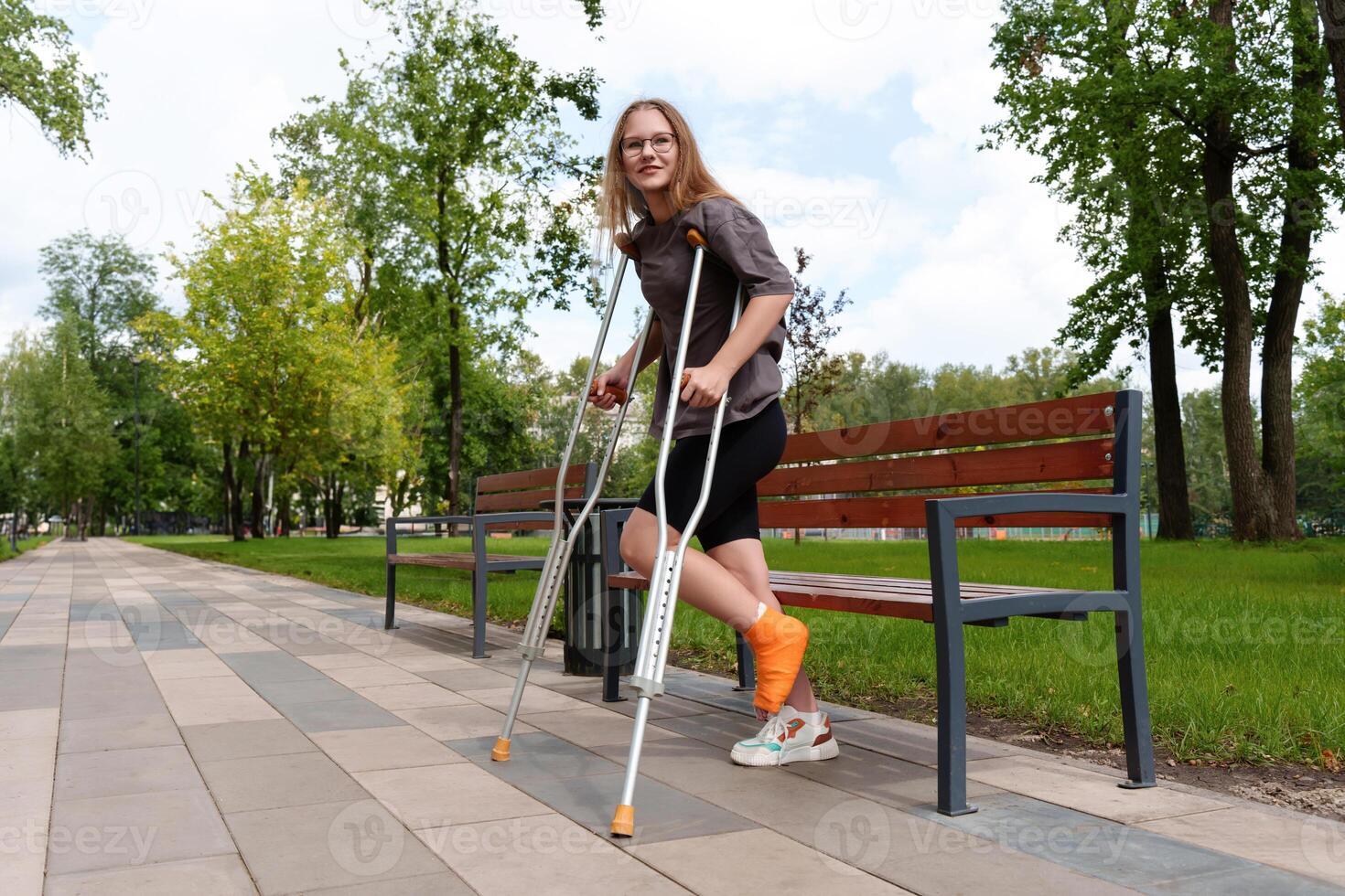teen in the park attempting to stand using crutches for cast-encased leg, suggesting need for mobility aids photo