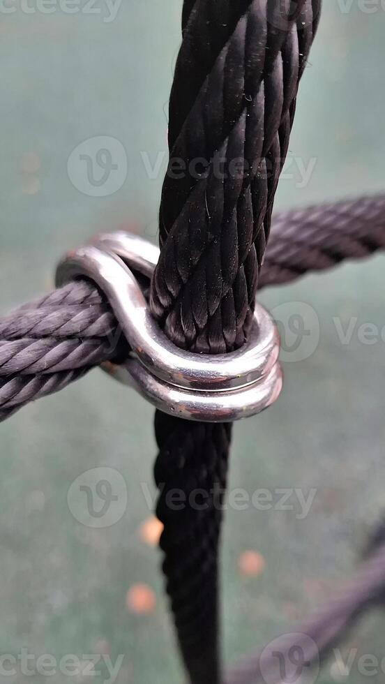 Close-up of black rope with metal clamp on green background photo