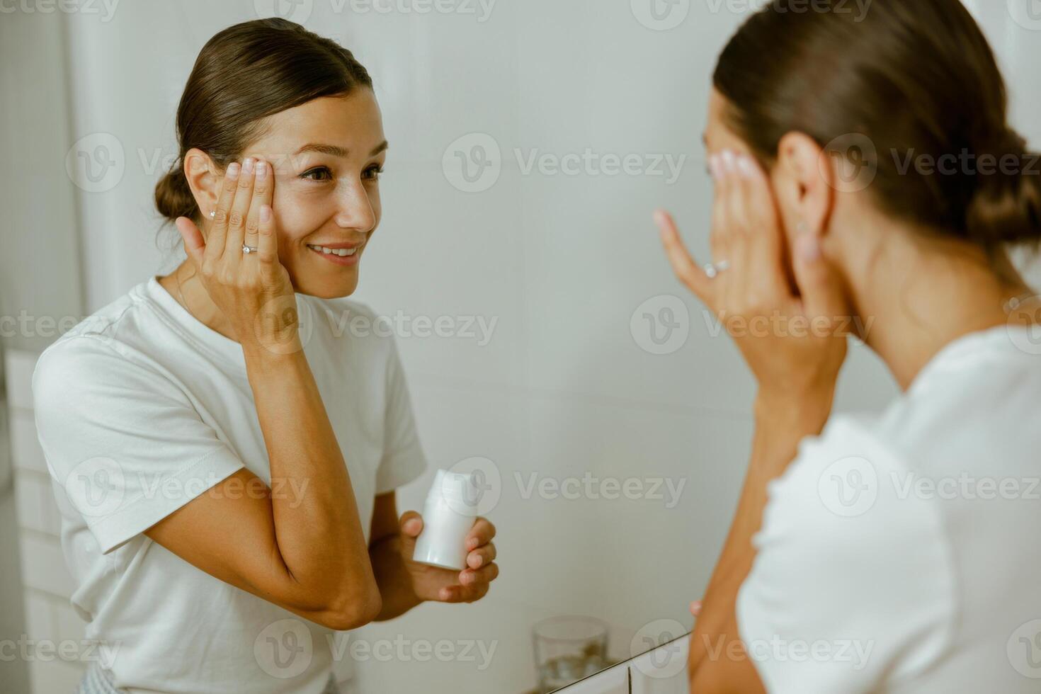 A Woman is Applying Her Skincare Routine in Front of a Mirror, Focusing on SelfCare and Beauty photo