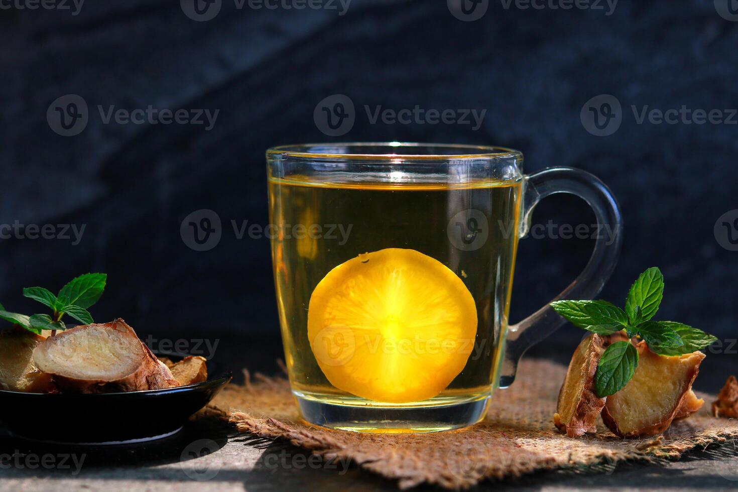 Cup of ginger tea with lemon and mint on a black background photo
