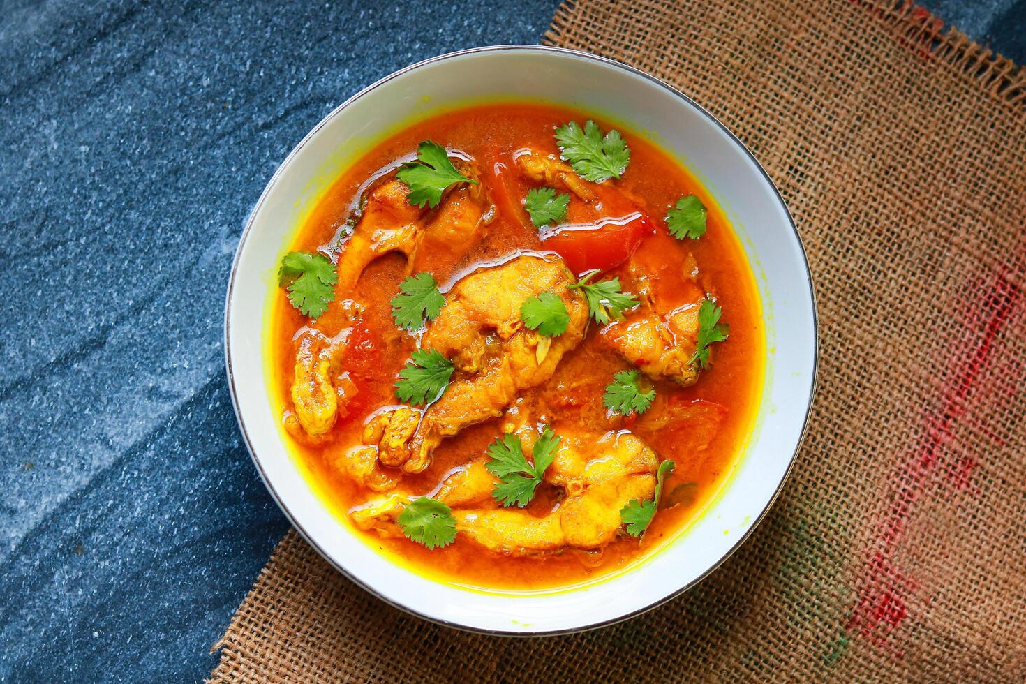 Fish curry in a white bowl on a black table. Top view, flat lay photo