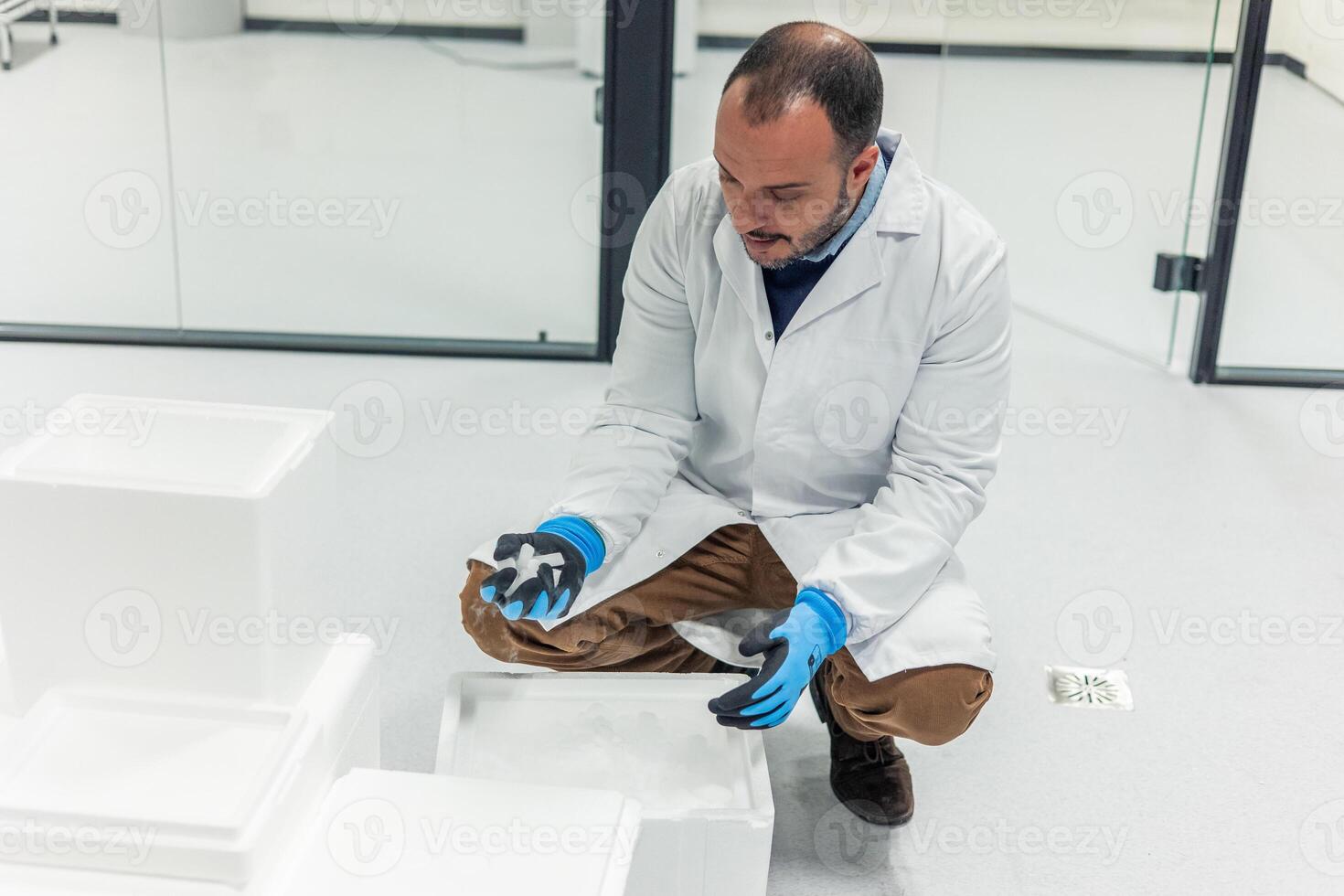 Scientist wearing lab coat and gloves handling dry ice in laboratory photo