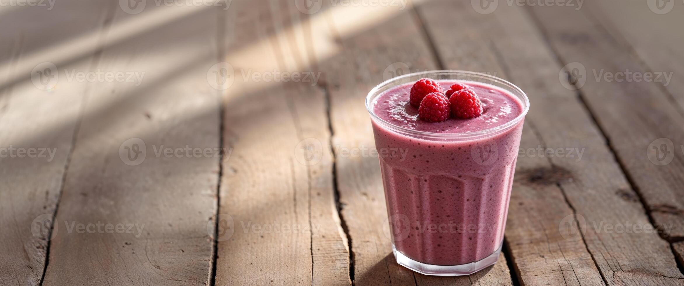 Refreshing Fruit Smoothie in Clear Cup with Raspberries on Wooden Table. photo
