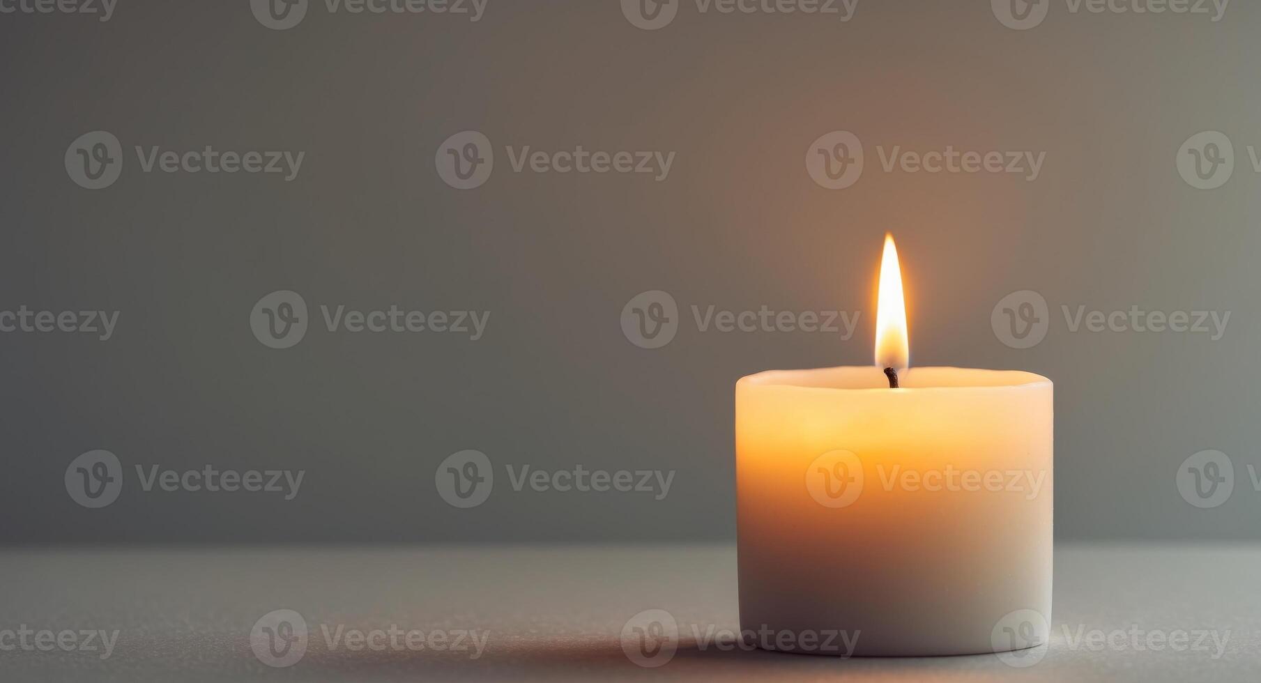 Single lit candle with a golden flame casting a warm glow in a serene setting photo