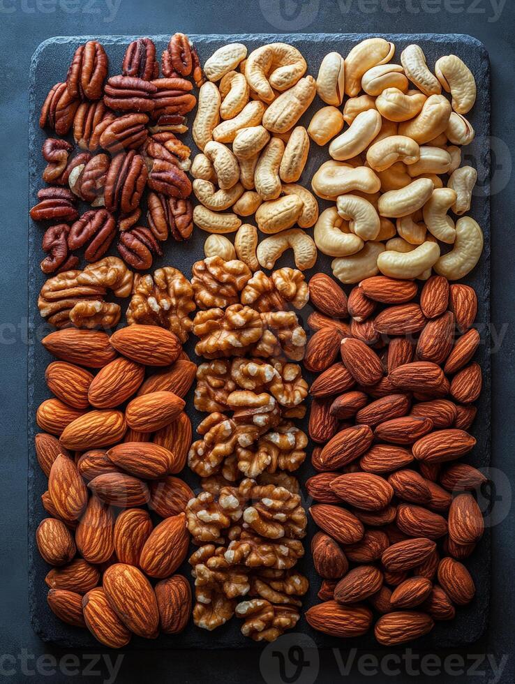 A colorful assortment of various nuts arranged neatly on a slate board. photo