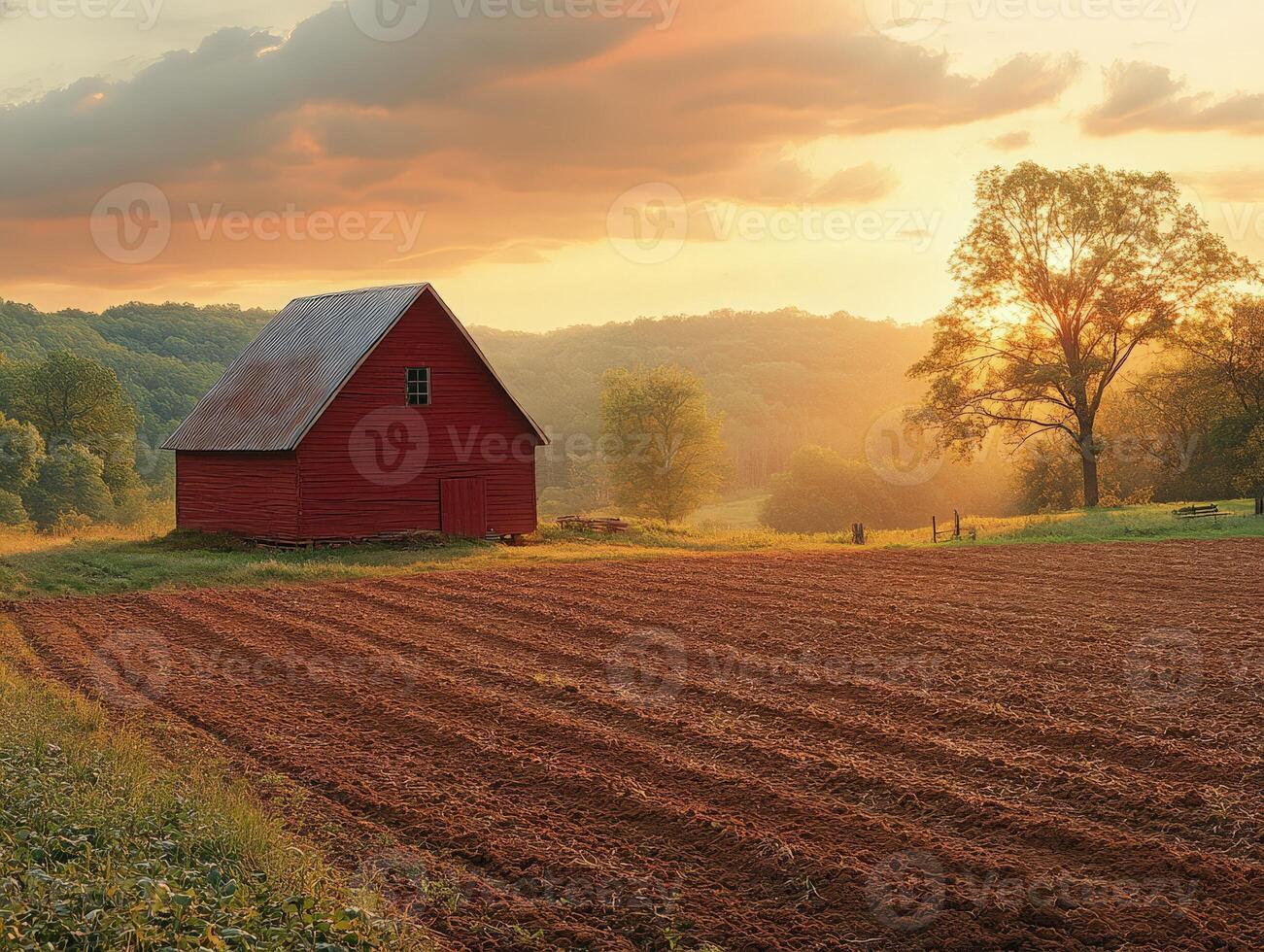 A serene sunset over a red barn and freshly plowed field in a rural landscape. photo