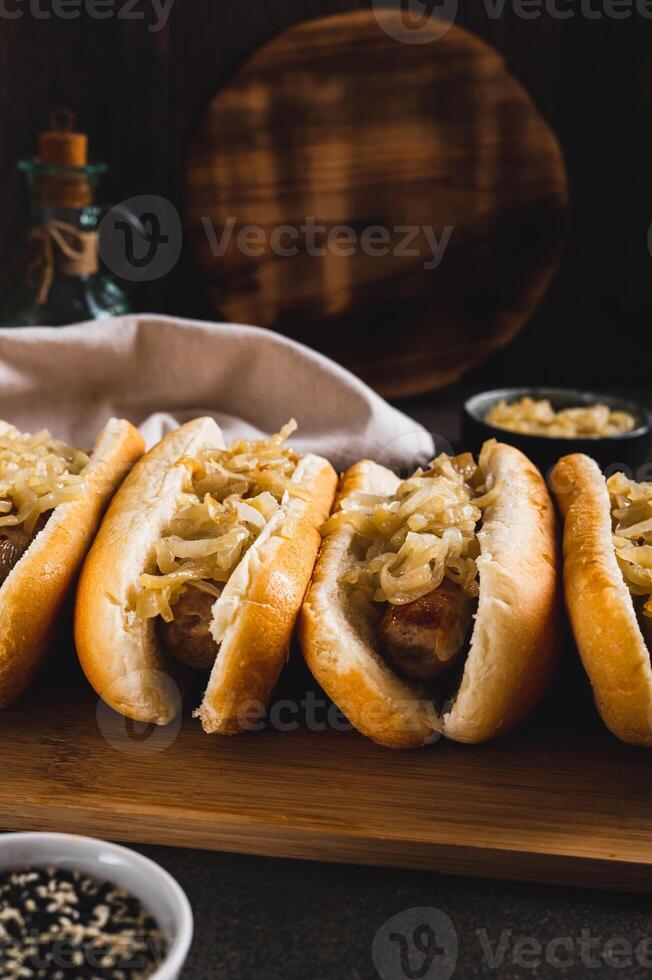 Homemade hot dogs with caramelized onions on a board on a table vertical view photo