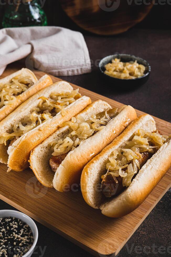 Delicious hot dogs with beef sausage and fried onions on a board vertical view photo