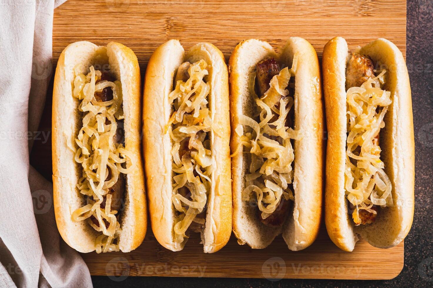 Close up of hot dogs with caramelized onions on a board on a table top view photo
