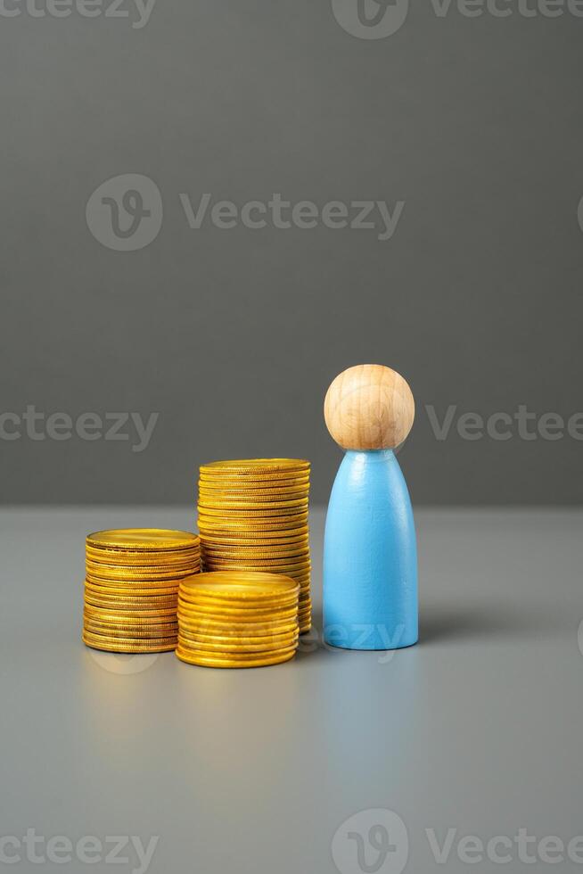 A figurine of a man and a stack of coins. Savings and capital. Purchasing power. Investments. Financial literacy, asset and resource management. Employee salary. GDP per capita. photo