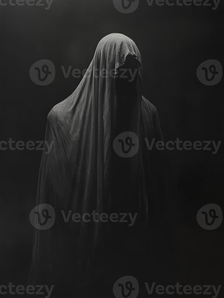 Mysterious figure shrouded in dark fabric against a shadowy background photo