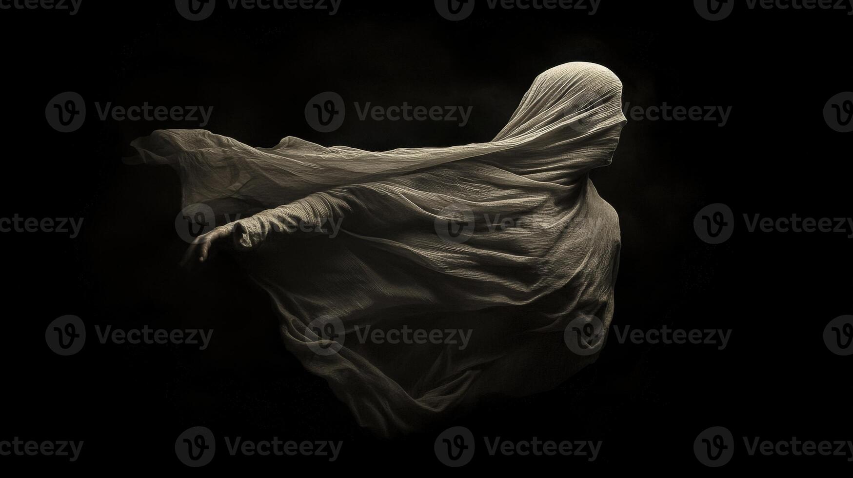 Mysterious figure draped in flowing fabric appears against dark background photo