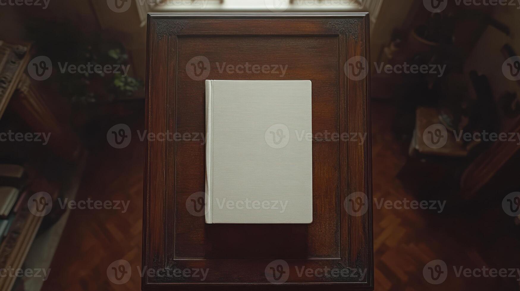 A solitary, blank book rests on a polished wooden table in soft light photo
