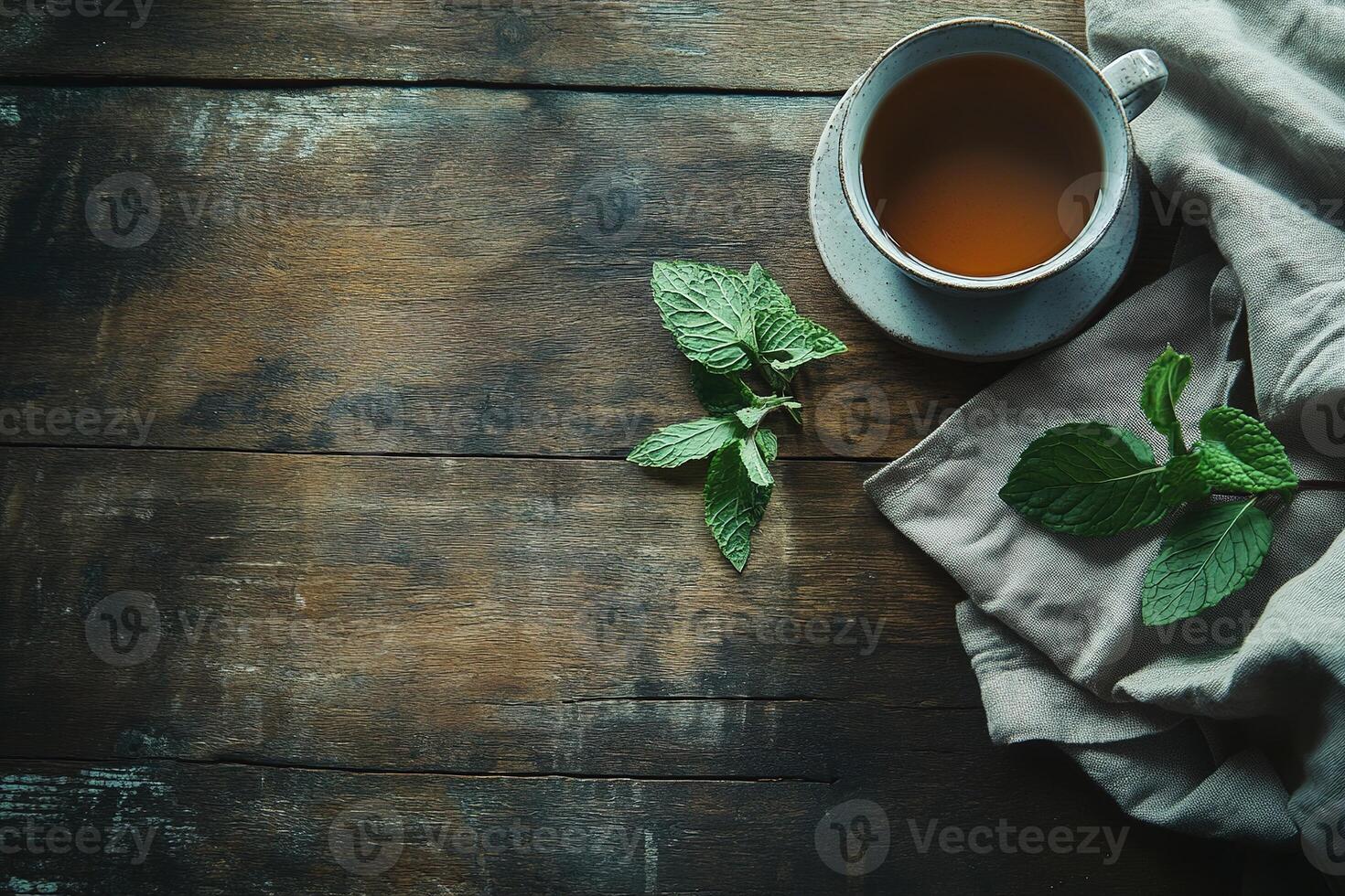 Rustic wooden table featuring a calming cup of herbal tea with fresh mint and a linen napkin in soft natural lighting photo