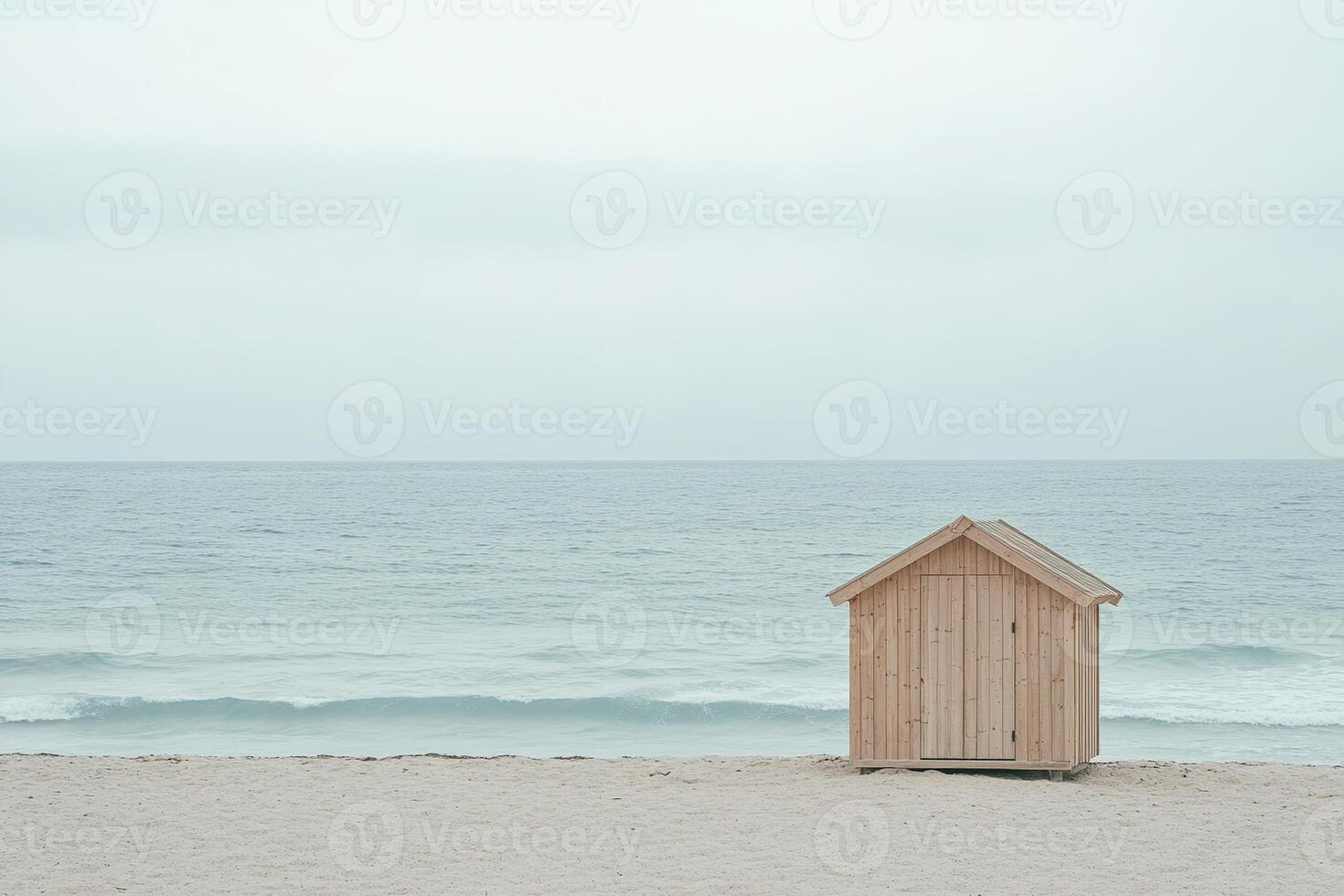A small wooden beach hut sits quietly on a smooth sandy beach, surrounded by soft waves and a calming atmosphere, perfect for relaxation and contemplation photo