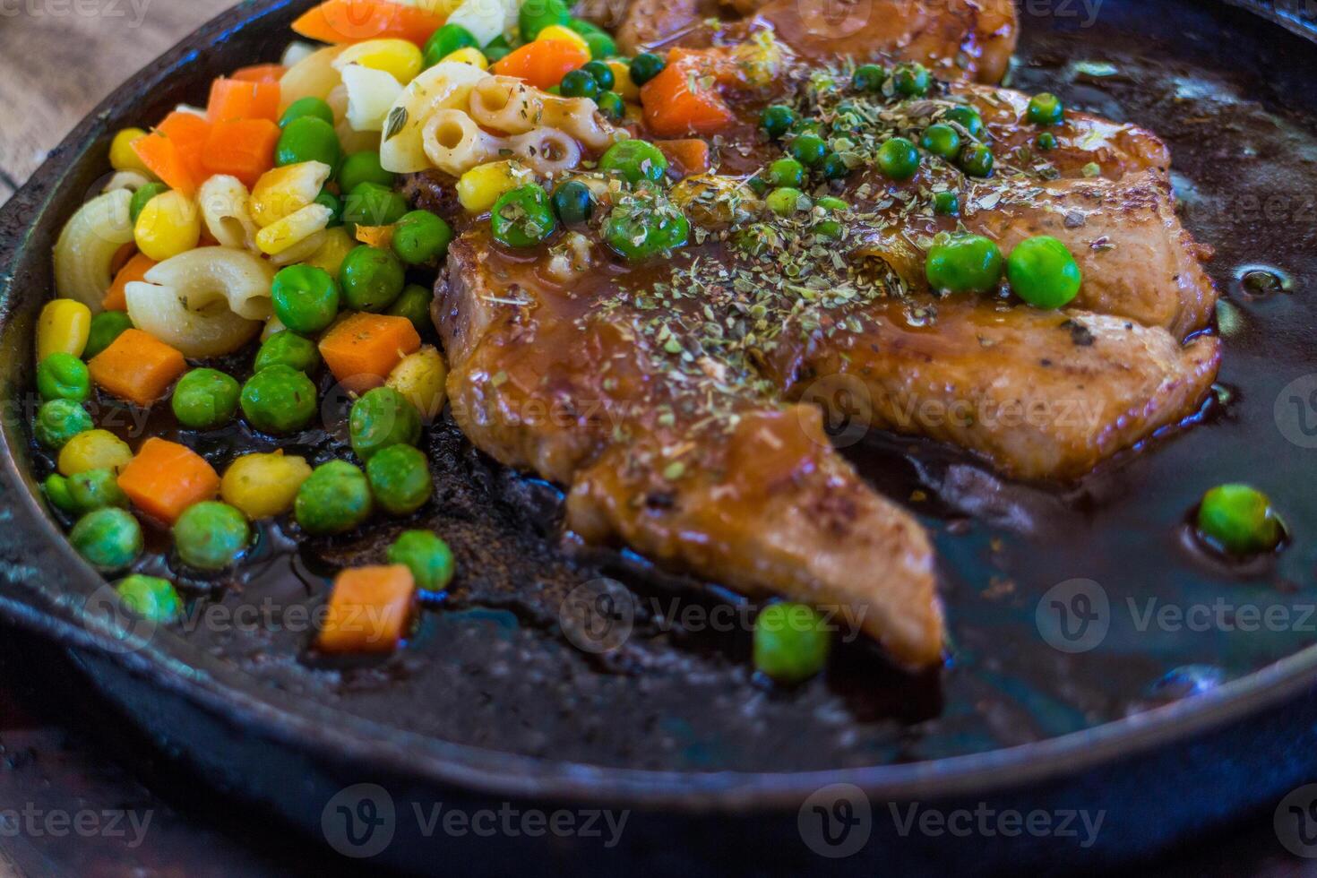 pork chops Steak corn, peas and carrots served in a hot pan. photo