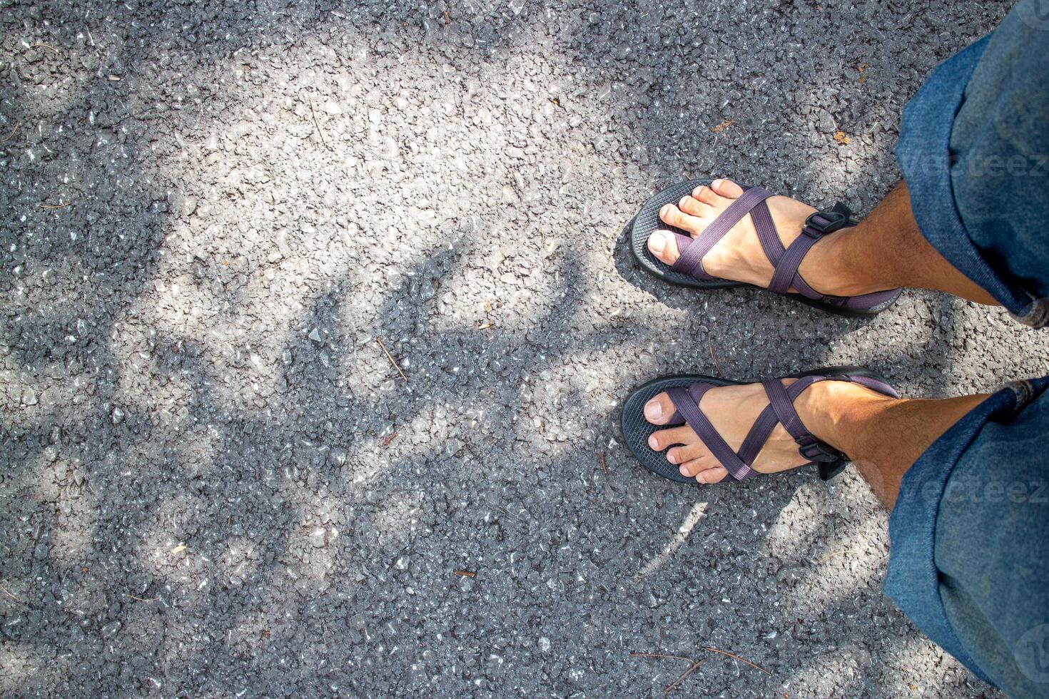Close up of male feet wearing sandals on the asphalt road. photo