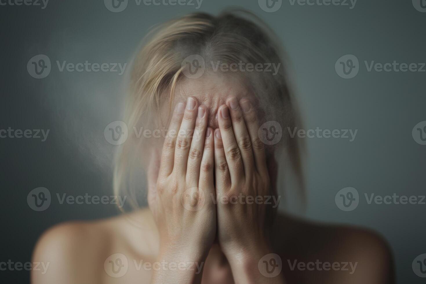 A person with blurred features covers their face with their hands, expressing emotion and vulnerability in a serene atmosphere photo