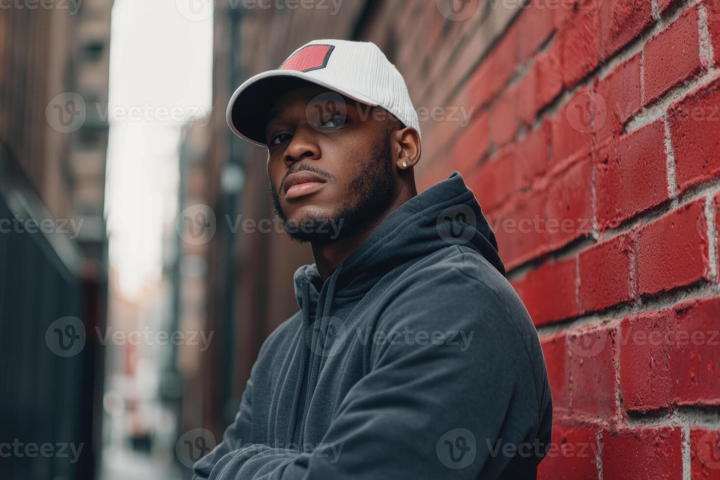 Young man posing confidently against a red brick wall in an urban alley on a cloudy day photo