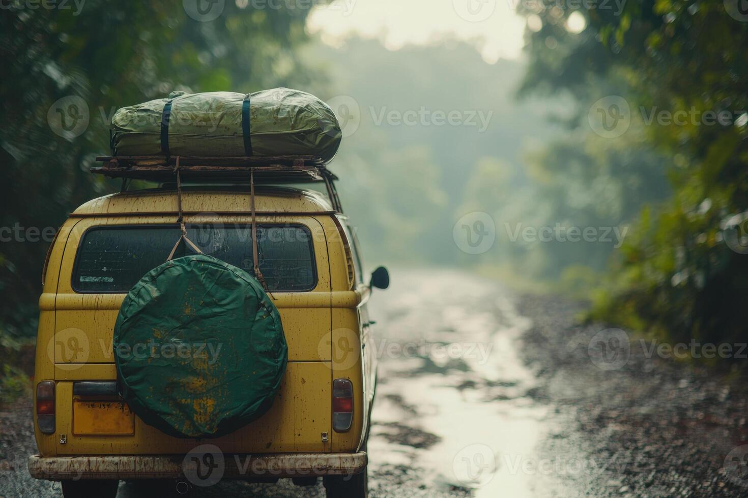 A yellow vintage van parked on a muddy road in a lush forest during a rainy day, ready for an adventure in nature photo