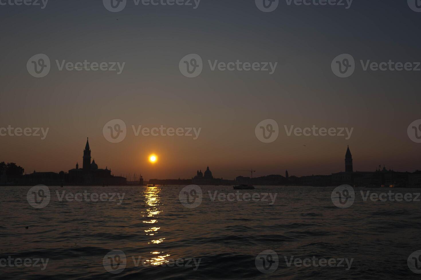 The sun is setting over the venice lagoon, creating a beautiful golden reflection on the water photo