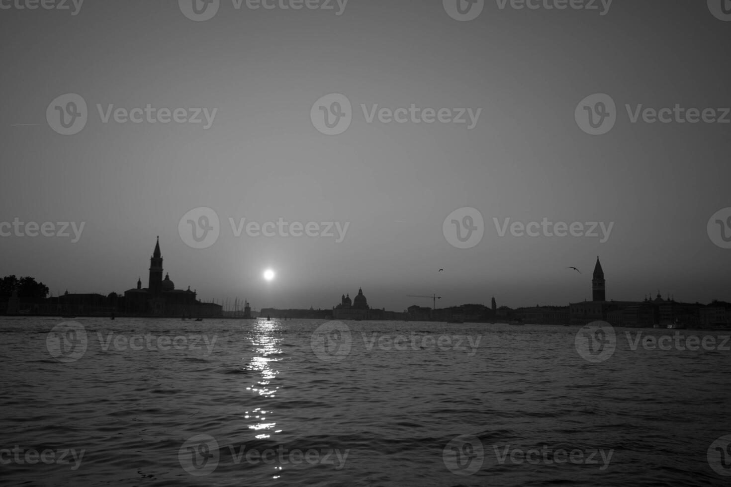 Sun setting on the horizon over venice, italy photo