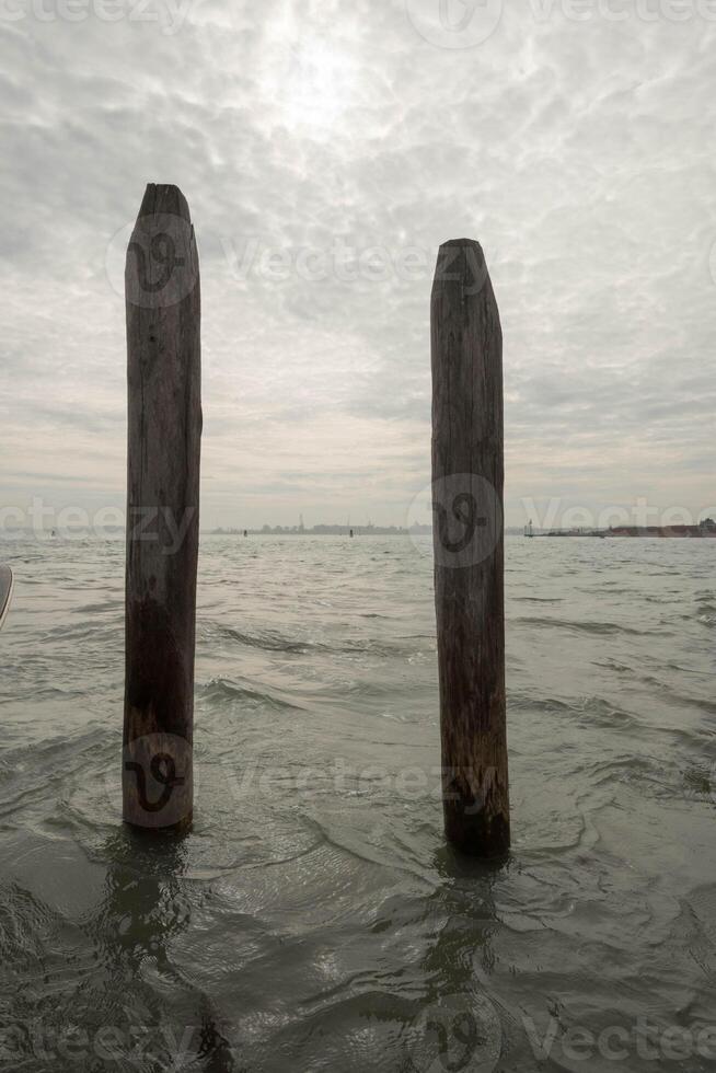 Two wooden poles emerging from venetian lagoon water photo