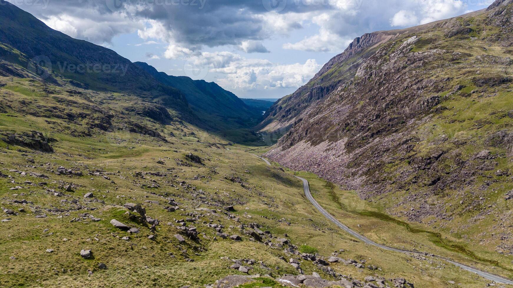 Breathtaking view of a winding road through a green rocky mountain valley under a blue sky photo