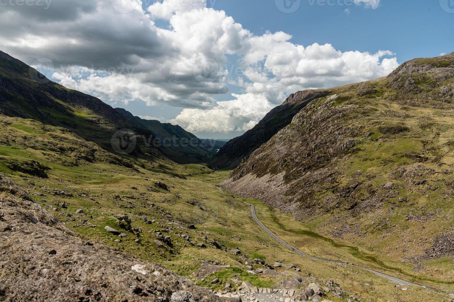Expansive view of a serene mountain valley with winding road under cloudy skies photo