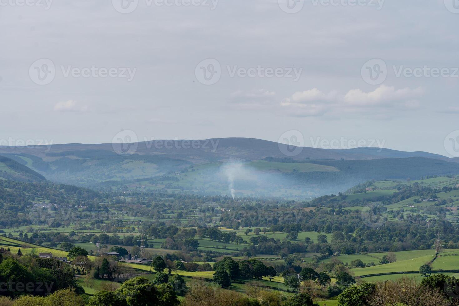 Expansive view of a misty green valley and rolling hills under a blue sky photo