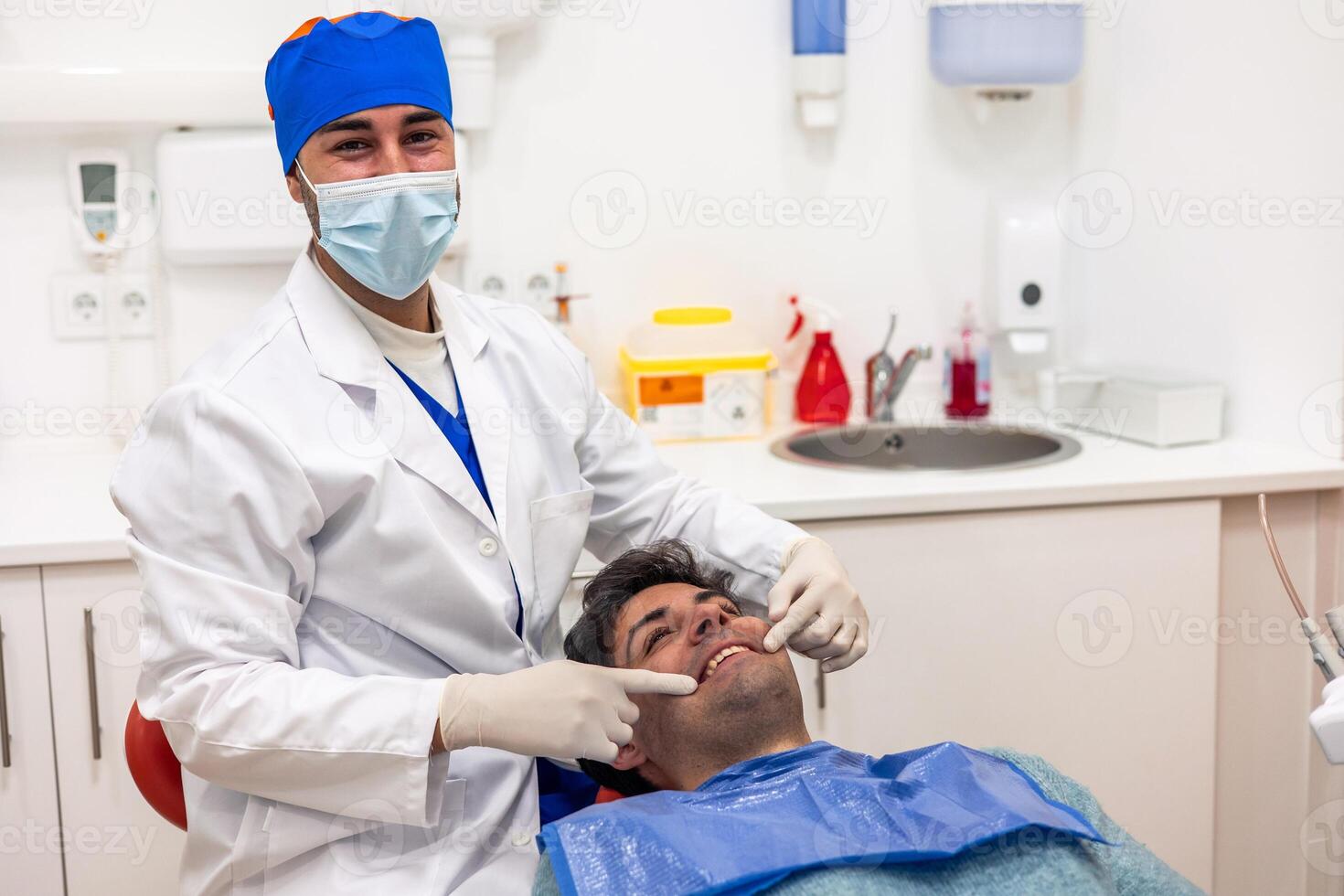 Dentist showing teeth with fingers to patient in dental clinic photo