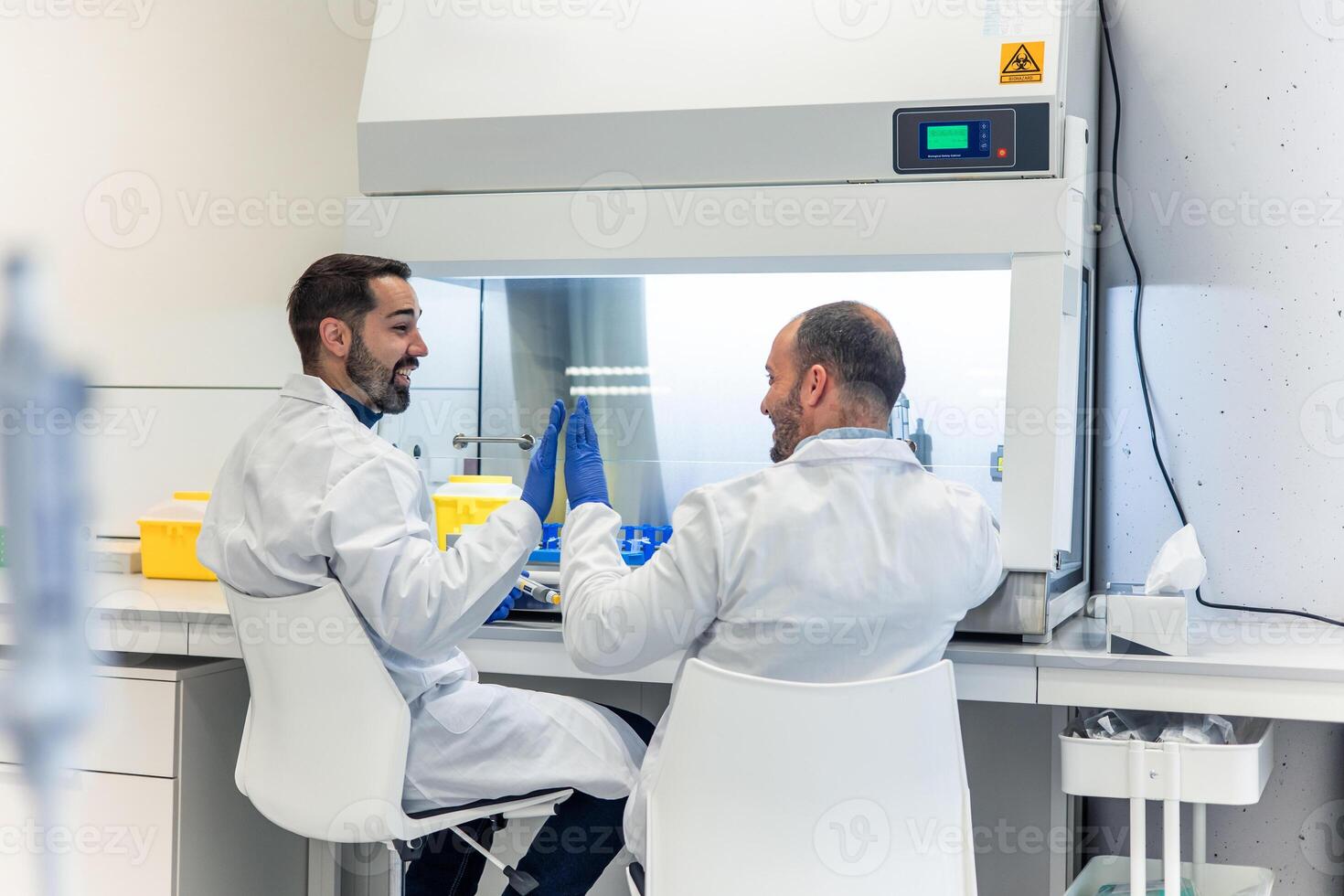 Two happy scientists giving high five celebrating successful experiment in laboratory photo