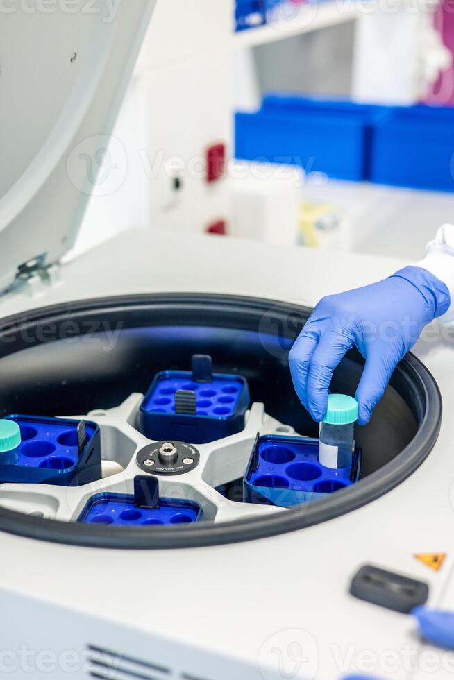 Scientist placing sample in laboratory centrifuge for testing photo