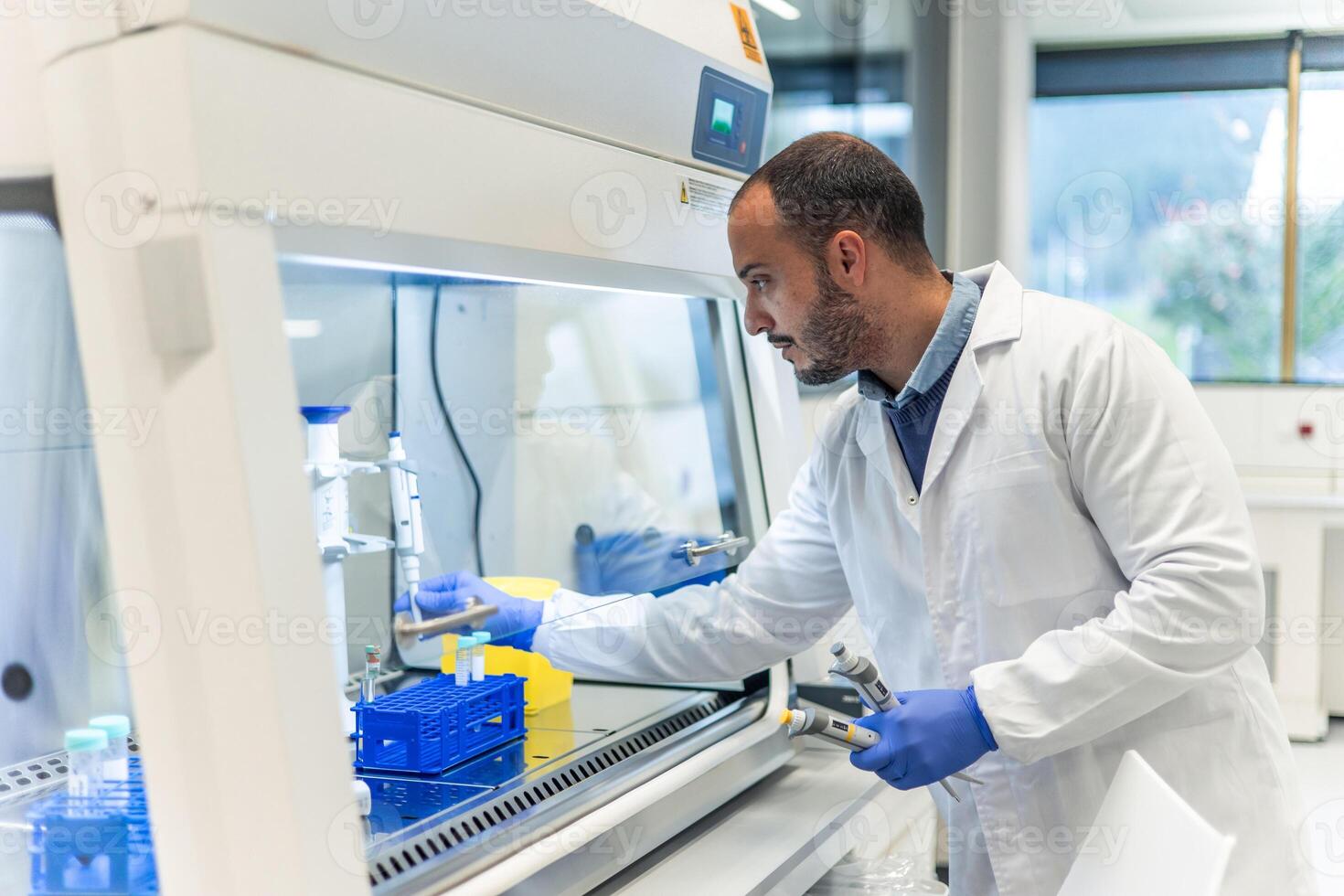 Scientist working with test tubes and multichannel pipette in laboratory fume hood photo