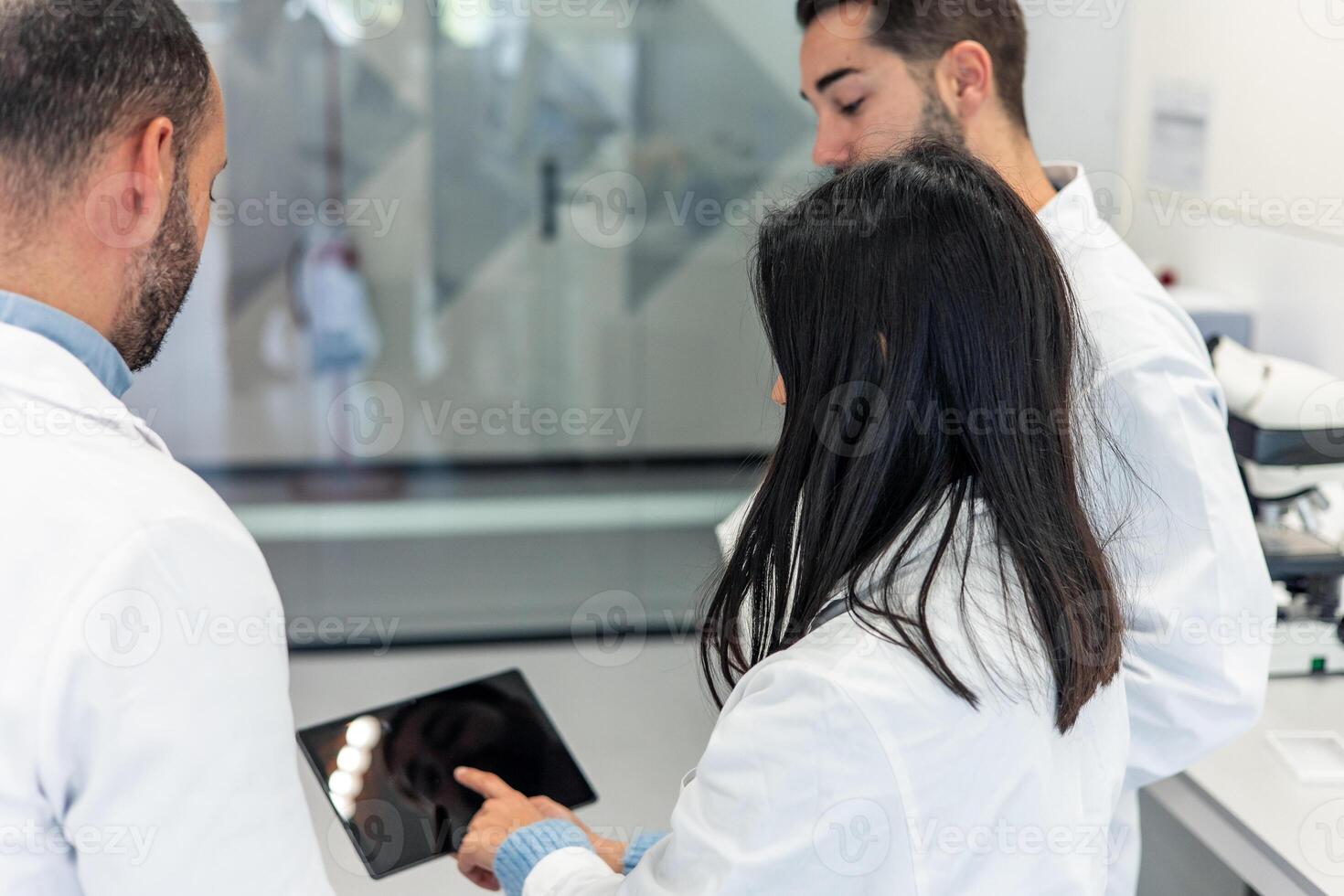 Scientists using tablet in laboratory discussing research photo