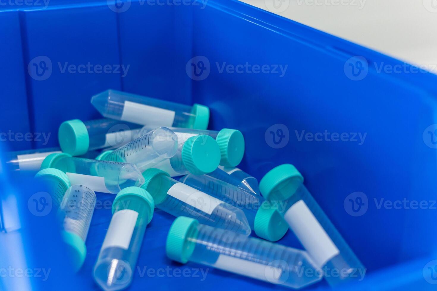 Empty test tubes with green caps lying in blue container in laboratory photo