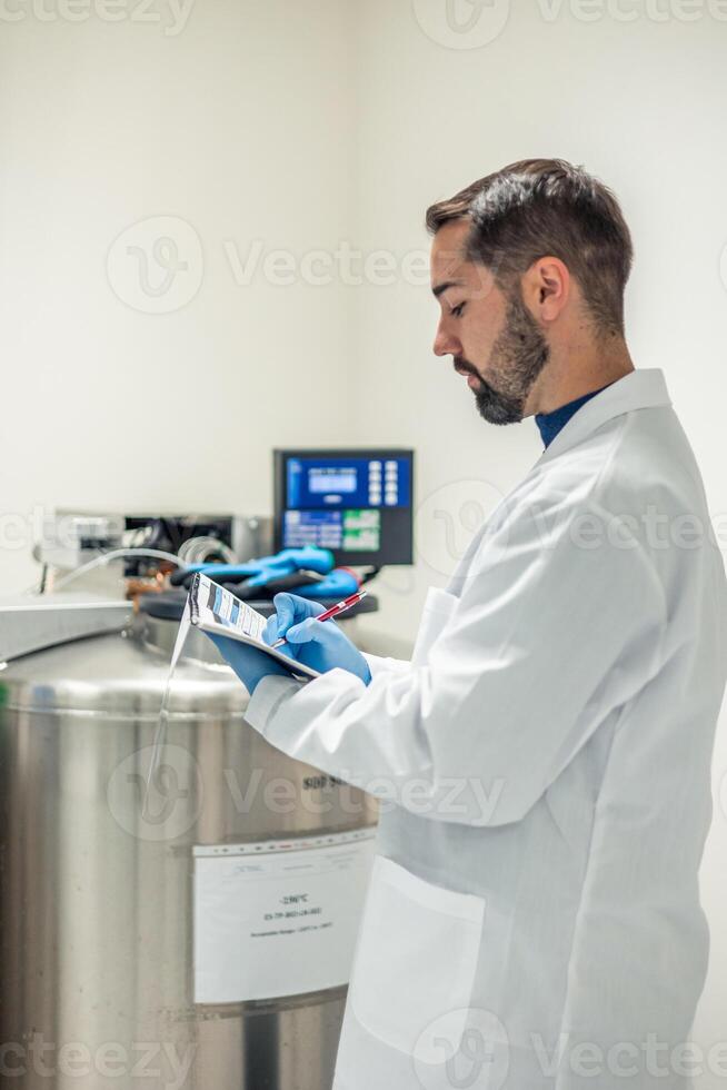 Scientist taking notes on a clipboard in laboratory photo